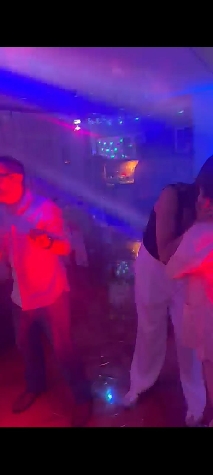 Pista de baile llena entre luces de colores y humo durante una fiesta