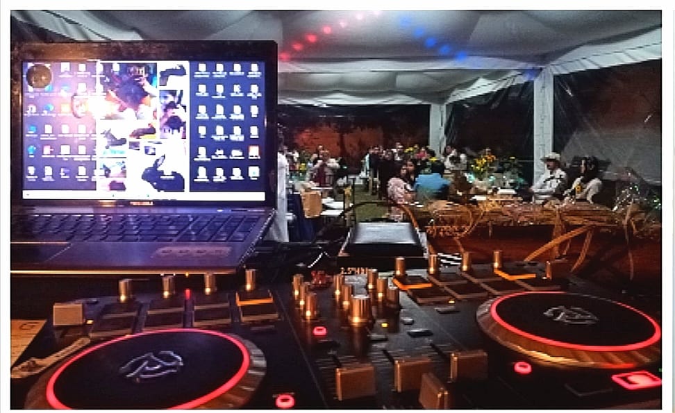 Cabina de DJ montada en un evento al aire libre con los invitados al fondo