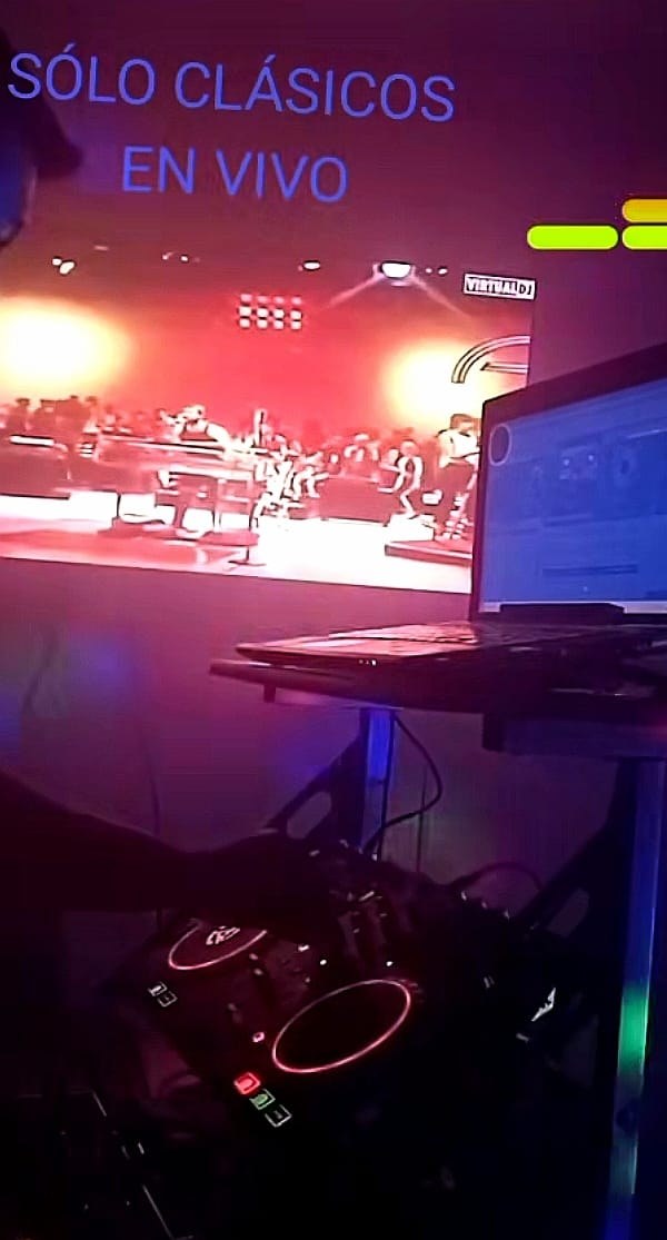 Cabina del DJ con pantalla de video y luces de colores durante un evento